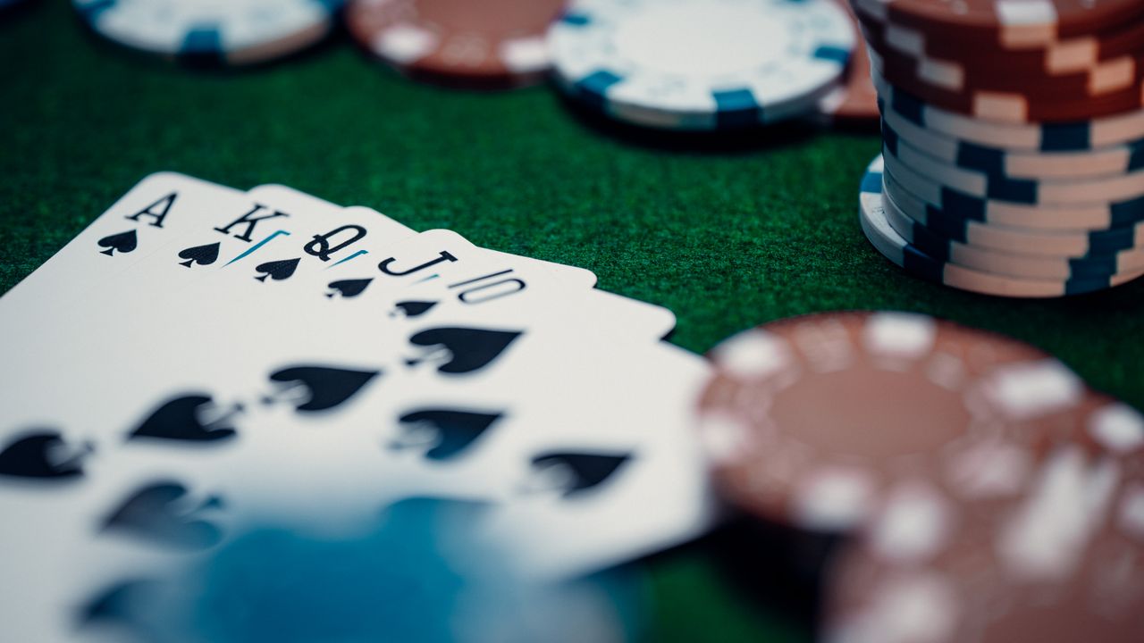 Royal flush in spades on green felt with stacked casino chips