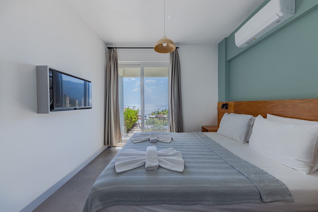 Bright suite with sage wall, timber headboard and a terrace looking toward open sky
