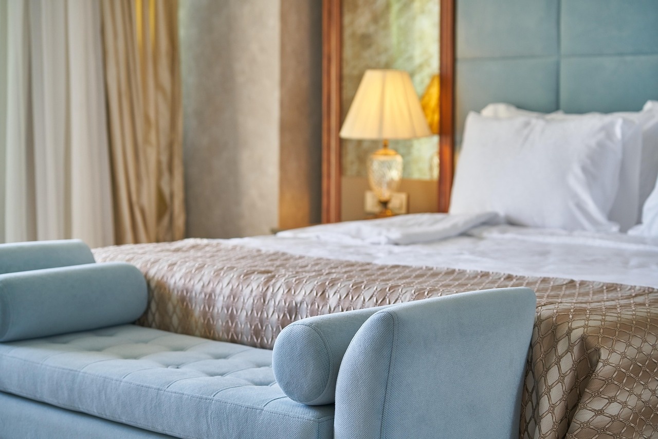 Deluxe room with tufted blue bench, champagne coverlet and crystal bedside lamp